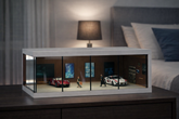 Model car display case on a nightstand with a bed and lamp in the background