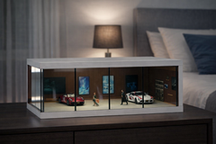 Model car display case on a nightstand with a bed and lamp in the background
